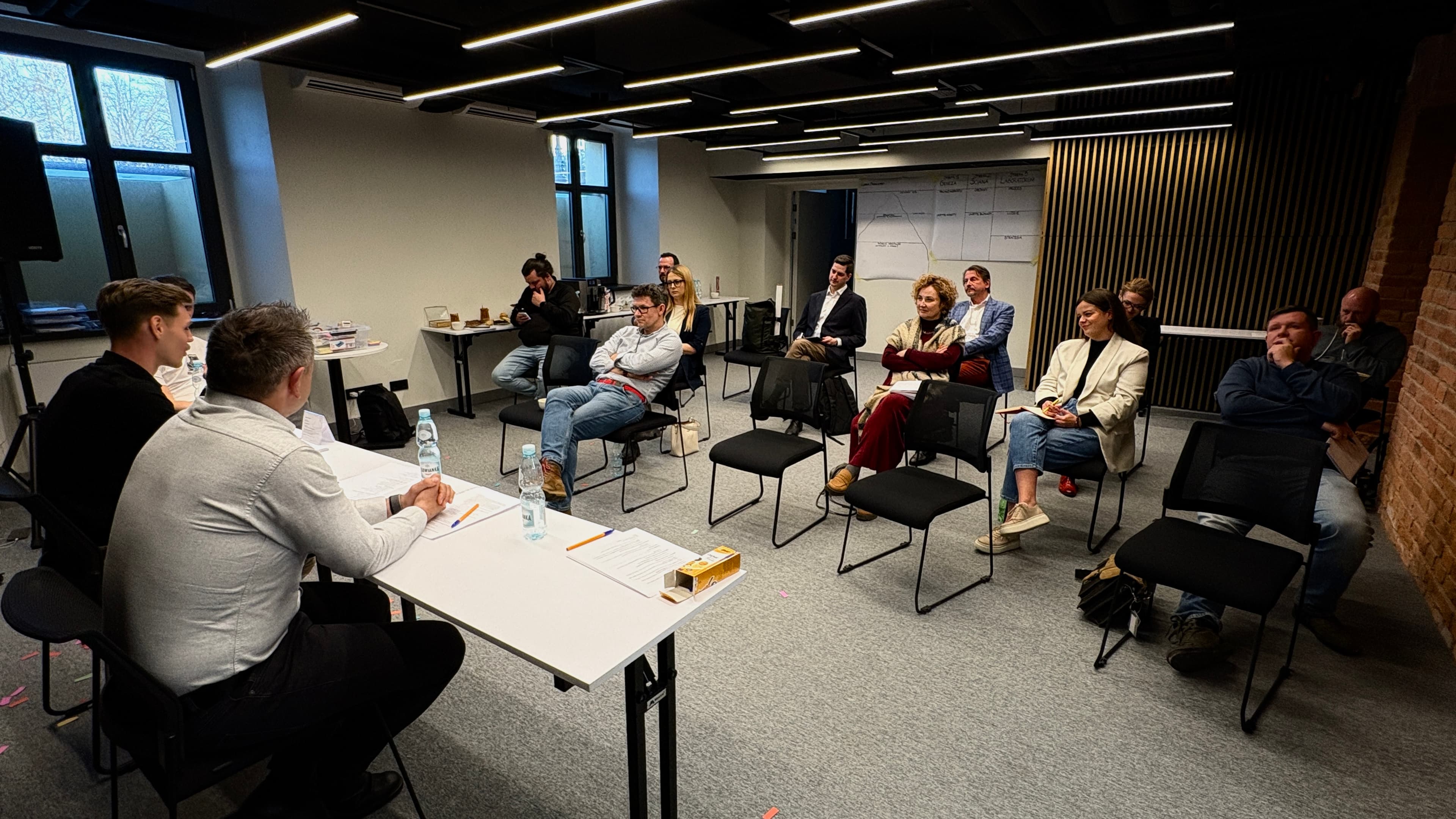 Uczestnicy POST-CI LAB siedzą w kręgu podczas rozmowy o realnych problemach firmy